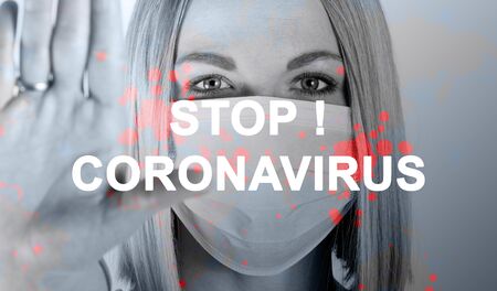 Close-up portrait of woman in medical mask with the inscription STOP Coronavirus with outstretched arm symbolizing the word STOP.の写真素材