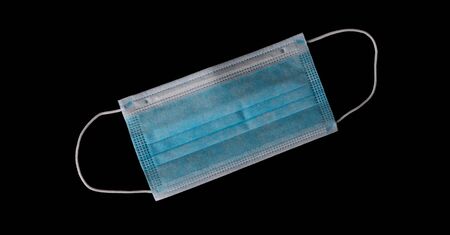 Medical mask with elastic bands for fastening on the ears isolated on a black backgroundの写真素材