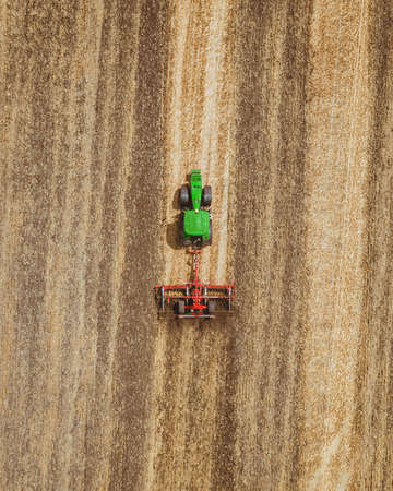 Aerial view of green tractor working in the field.の写真素材