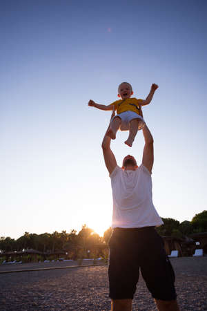 Father and son having fun on the beach at sunsetの写真素材