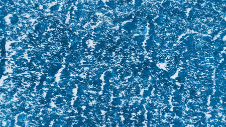 Blue ice surface with scratches and snowの写真素材