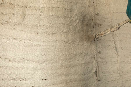 The process of applying plaster to walls inside a building by machine.の写真素材