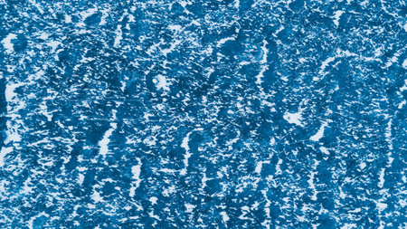 Blue ice surface with scratches and snowの写真素材