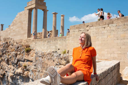 Black Hipster traveler smiling sitting in ruins, on the background of the Parthenon on the Acropolis of Athens, Greece. Vacation woman enjoying the visit in Athensの写真素材