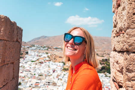 A blonde woman looks at the panorama of Lindos on the island of Rhodes, Greeceの写真素材
