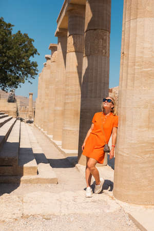 A woman stands in the ancient acropolis of Lindos against the background of the colonade, Greece, Rhodesの写真素材