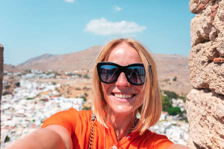 A blonde woman looks at the panorama of Lindos on the island of Rhodes, Greece