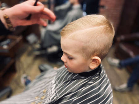 Master cuts a little boys hair in a barbershopの写真素材