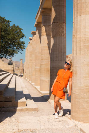 A woman stands in the ancient acropolis of Lindos against the background of the colonade, Greece, Rhodesの写真素材