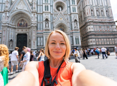 Young woman tourist taking photo near Cathedral of Santa Maria del Fiore, Florence, Italyの写真素材