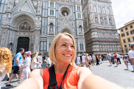 Young woman tourist taking photo near Cathedral of Santa Maria del Fiore, Florence, Italyの写真素材