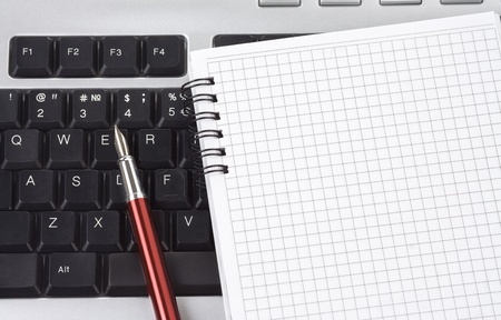 computer keyboard and ink pen with notebook