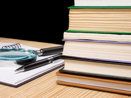 pile of book and pen on notebook on black backgroundの写真素材