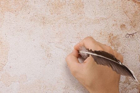 writing male hand with feather on backgroundの写真素材