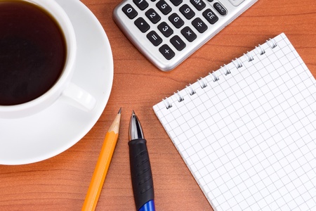 checked notebook and cup coffee in office