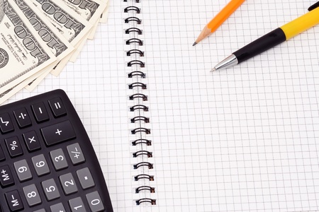 pen, pensil, calculator and dollars on checked padの写真素材