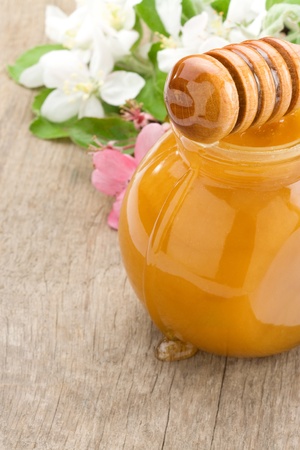 honey in glass and stick with blossom on wood backgroundの写真素材