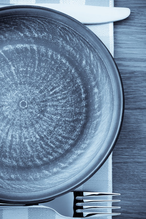 plate, knife and fork at napkin on wooden backgroundの写真素材