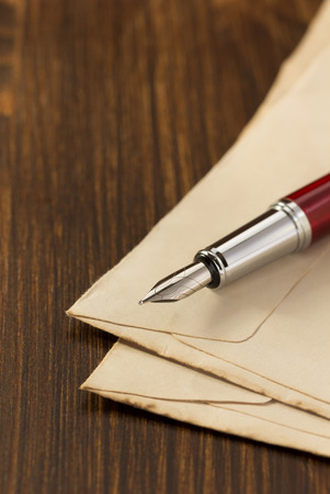 ink pen and old envelope on wooden backgroundの写真素材