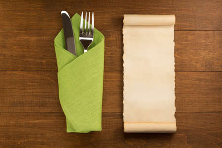 knife and fork at napkin on wooden background