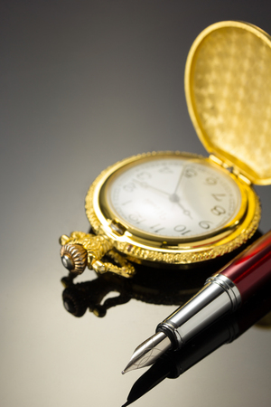 pocket watch and ink pen on black backgroundの写真素材