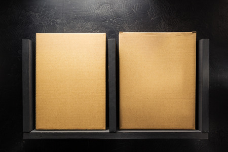cardboard box on wooden shelf at black background surfaceの写真素材