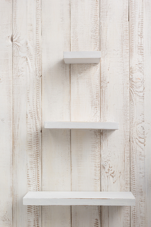 wooden shelves at white wall background textureの写真素材