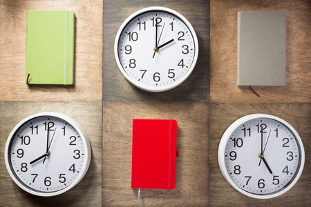 notebook and wall clock at wooden background surfaceの写真素材