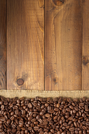 coffee beans at sack hessian burlap on wooden background, top viewの写真素材