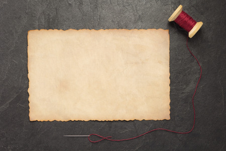 spool of thread and needle on slate stone background, top viewの写真素材