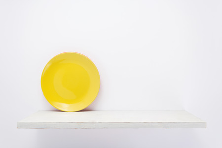 plate at wooden shelf on white backgroundの写真素材