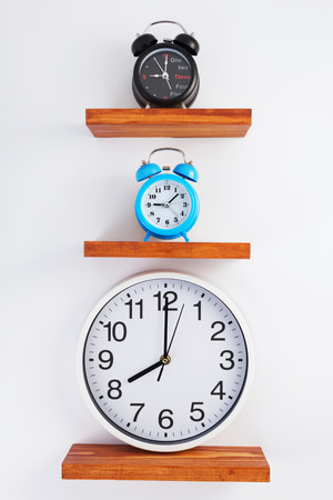 alarm and wall clock at wooden shelf on white backgroundの写真素材