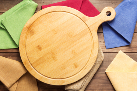 pizza cutting board and kitchen napkin cloth at rustic wooden plank board background, top viewの写真素材