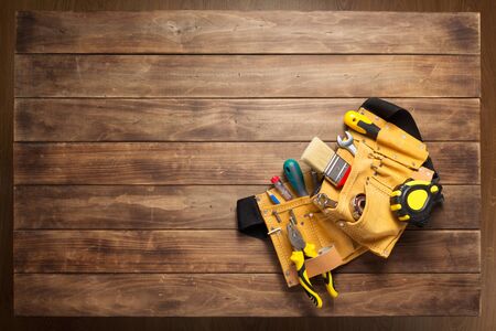 instruments in tool belt at wooden table surface background