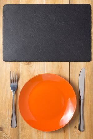 plate, knife and fork at rustic wooden plank board table background, top viewの写真素材