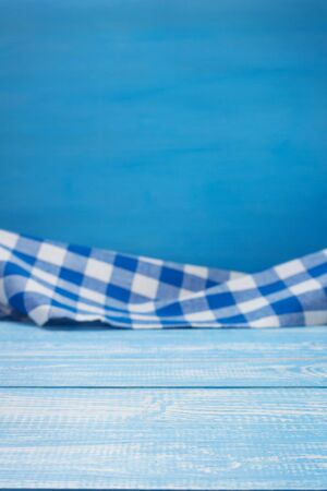 Cloth napkin at blue rustic table in front, wooden plank boardの写真素材