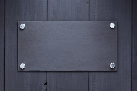 nameplate at black wooden background texture surface, with screwsの写真素材