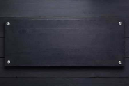 wooden nameplate at black background as texture surface with screwsの写真素材