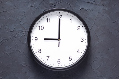 wall clock at dark grey painted concrete texture or putty background
