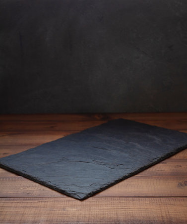 slate stone tray at wooden table, with wall background texture