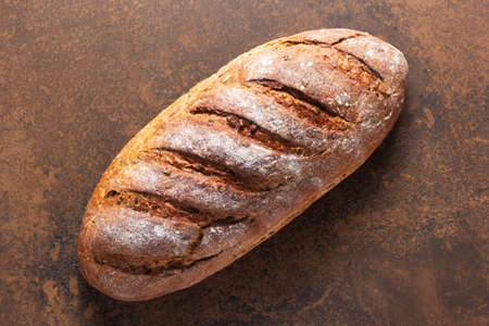 Loaf of fresh bread on table. Bakery food at stone natural background texture. Flat lay top view