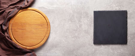Pizza cutting board and cloth napkin on stone surface of table. Food recipe concept at tabletop or...