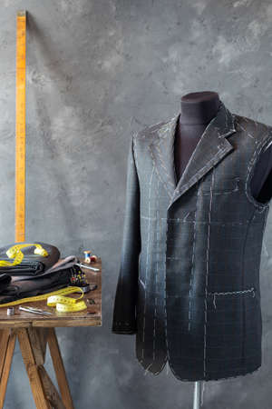 suit jacket on male tailor mannequin and sewing tools, creative concept of clothes atelierの写真素材