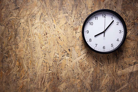 Clock watch at wooden chipboard of wall surface background texture. Top or front view