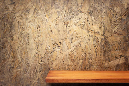 Wooden shelf or tabletop near chipboard wall background. Front view of shelf or tableの写真素材