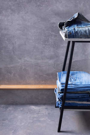 Denim jeans at chair or shelf of rack near grey wall background texture. Front view of classic jeans fashionの写真素材
