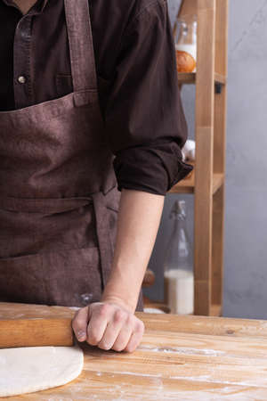 Baker man kneading or making dough with rolling pin and bakery ingredients for homemade bread...