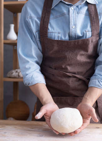 Baker man kneading or making dough and bakery ingredients for homemade bread cooking on shelf....