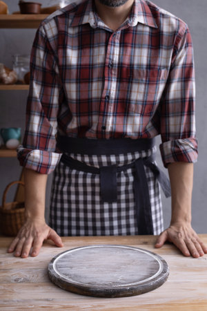 Baker man and pizza board and bakery ingredients for bread cooking on shelf. Bakery concept near wall background textureの写真素材