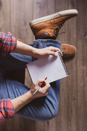 Men's hand holding pen and notebook. Student male hand writing or drawing by pen, top viewの写真素材